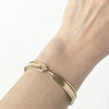 A solid 10K yellow gold ridged bangle. Bracelet has a hook closure, which is a both  unique and functional element.